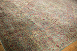 Corner detail of a vintage Kerman rug showing its thousand-flower border in soft, faded tones.