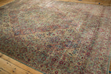 Perspective view across the floral field and borders of a distressed vintage Kerman carpet.