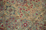 Distressed pile of a vintage Kerman carpet with lattice and floral details in blue and red.