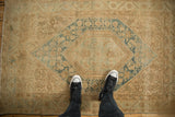 Distressed vintage Sarouk rug showing beige field, dusty blue hexagonal pattern, and worn floral texture.