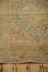Distressed Sarouk rug showing beige floral border, fringe, and even wear.