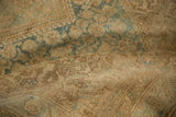 Distressed pile of the vintage Sarouk rug showing faded beige, dusty blue floral motifs and wear.