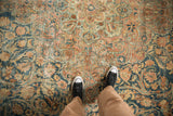 Distressed vintage Kerman carpet's textured field featuring softened dusty blue and rose floral arabesques.