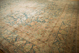 Distressed Kerman carpet corner with muted dusty blue and antique ivory floral arabesques.