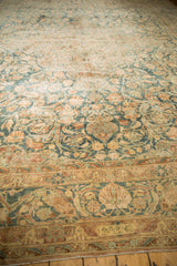 Distressed Kerman carpet section with muted sapphire, rose, and ivory floral arabesque design.