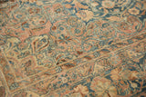 Distressed vintage Kerman carpet detail: dusty rose and sapphire floral motifs with visible knot heads.