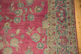 Corner of an antique Lilihan carpet showing the magenta floral field and intricate, dusty teal border pattern.