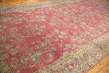 Angled perspective on the distressed texture and floral bouquets of an antique Lilihan carpet.