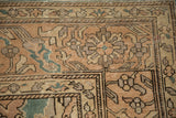 Sparta carpet corner detail with distressed floral palmettes in dusty teal, sand, and beige.