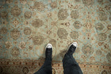 Softly distressed texture on a vintage Persian rug with beige floral vines over a powder blue field.