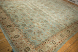 Angled perspective on a vintage distressed Meshed carpet with a powder blue and brown floral design.