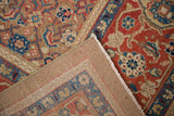Folded corner of an antique Persian carpet showing the hand-woven foundation and machine-bound edge.