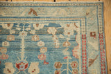 Distressed vintage Lilihan rug corner showing heavily worn blue floral field and arabesque vine border.