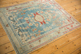Distressed Lilihan rug corner, displaying abrashed sky blue field and red border.