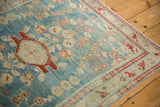 Corner detail of a vintage distressed Lilihan rug with cherry red arabesque and vine border.