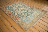 A vintage Mehreban rug's Caucasian-inspired design shown from an angle with heavy color variation.