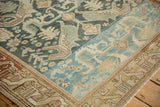 Corner view of a vintage rug with serrated leaves and a serpent-like geometric border.