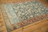 Angled view of a distressed Mehreban rug's sprawling design in dusty teal and rust border.