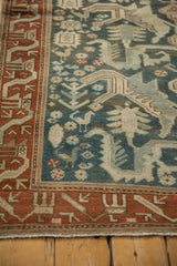Corner view of a Mehreban rug's serpent-like border in rust and dusty blue field with bird motifs.