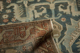 Folded corner of a distressed Persian rug showing the hand-knotted weave and dusty teal pile.