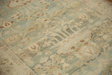 Close-up of distressed vintage Hamadan rug with faded blue, ivory, and green floral patterns.
