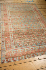 Angled view of a distressed Kurdish rug showing its allover lattice pattern and heavy abrashes.