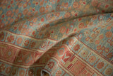 Distressed nubby texture of a Kurdish rug with plant motifs in powder blue and raspberry red.
