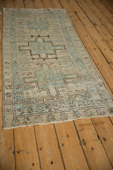 Distressed Karaja runner corner, dusty blue geometric border, starburst petals, and soft wear.