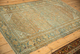 An angled view of the vintage Bibikabad rug showing its distressed texture and Turtle Samovar border.