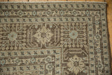 Distressed Tabriz carpet corner featuring geometric borders, soft dusty blue accents, and a worn texture.