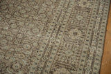 Distressed Tabriz rug close-up: worn pile, faded Herati pattern, and charcoal, ivory tones.