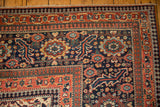 Corner detail of antique Joshegan carpet, with madder red serrated leaf and navy pawn motifs.