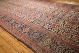 Intricate patterning of antique Joshegan carpet's ivory field, navy border, and pawn motifs.