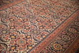 Detail of antique Persian Joshegan carpet showing ivory field, madder red florals, and pawn motif border.