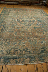 Faded teal vinery on distressed coffee brown Persian Bijar rug with fringe.
