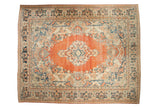 Distressed vintage Arak carpet with a terracotta medallion, navy blue florals, and sand accents.