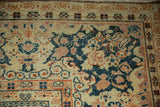 Low pile texture of a distressed Arak carpet with scrolling navy floral designs and a terracotta border.