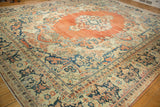 Angled view of a vintage Arak carpet's worn pile, showing terracotta and navy Rococo-style leaves.