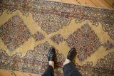 A perspective view of the vintage Kerman runner's time-softened texture and ochre field.