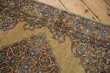 Corner detail of a tea washed Kerman rug showing its low pile and intricate scrolling pattern.