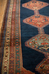 Angled view of an antique Bijar rug's geometric border beside the serrated medallion on a navy field.