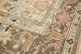 Distressed Lilihan carpet detail, showing spiral arabesque border with faded magenta and terracotta.