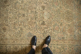 Overhead detail of a distressed Kerman carpet's floral arabesque pattern and low, worn pile.