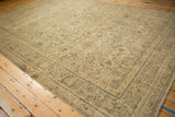 Angled perspective of a distressed Kerman carpet with interconnected floral arabesques in soft, neutral tones.