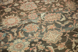 Heavy abrashes on the distressed charcoal field showing low pile and intricate floral patterns.