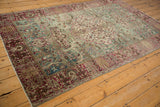 Distressed vintage Tabriz rug lower corner, displaying faded teal, cranberry, and ivory weeping willow border.