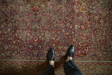 Distressed raspberry field with scrolling arabesques and palmette border, Meshed carpet.