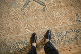 Time-softened pile of a distressed Heriz carpet showing geometric patterns in sand, brown, and dusty teal.