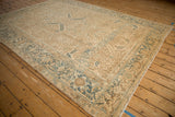 Angled view of a vintage distressed Heriz carpet showing its even wear and sand-colored field.