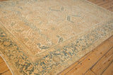 Angled view of a vintage Heriz rug's distressed beige field and dusty teal Turtle Samovar border.